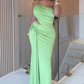 Woman in a green evening gown standing indoors.
